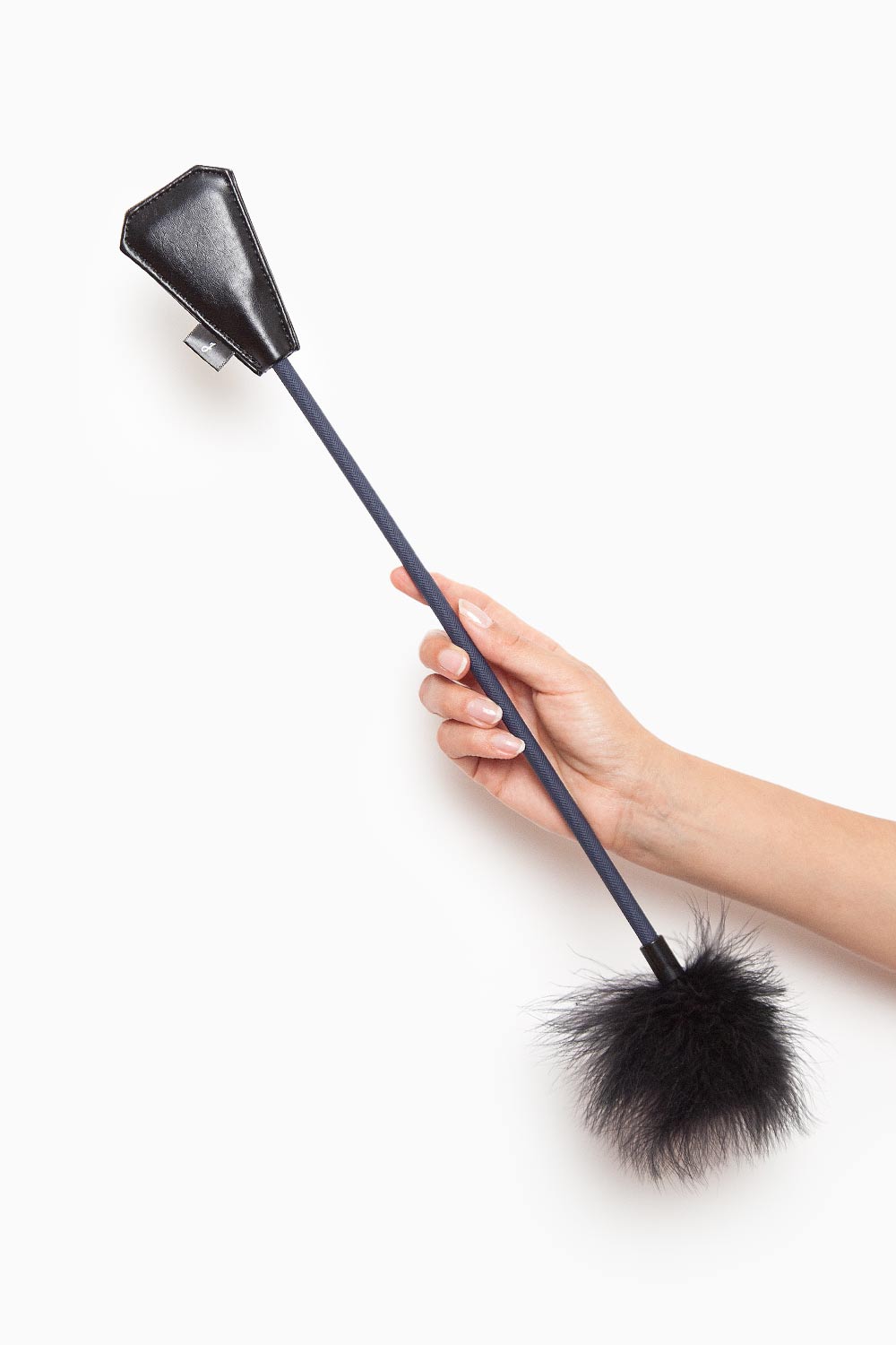 Mano mostrando fusta del Kit Atrevida, combinación de pluma y impacto para estimular el deseo