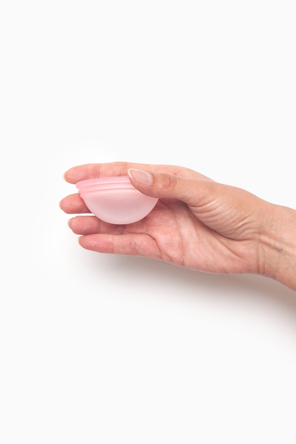 Mano sosteniendo disco menstrual reutilizable de silicona médica, apto para usar durante el sexo